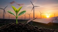 Green plant seedling growing from soil with wind turbines and solar panels at sunset representing renewable energy and sustainable development.