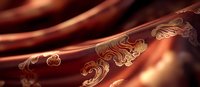 Luxurious brown silk fabric with golden floral ornaments flowing in elegant waves creates rich textile background for luxury design projects.