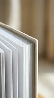 Close-up of open book pages with shallow depth of field showing paper texture and binding details for educational and literary content.