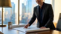 Caucasian male professional in dark business suit reviewing architectural blueprints at modern office desk with city skyline view, suitable for corporate, business planning, and architecture concepts.
