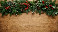 Festive evergreen garland with red berries and gold bells arranged on rustic wooden surface, ideal for holiday decorating and seasonal marketing materials.