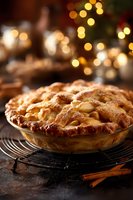 Homemade apple pie with golden lattice crust on cooling rack with festive holiday lights in background, creating warm atmosphere for seasonal gatherings.