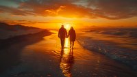 Romantic couple walking hand in hand on beach at golden sunset with dramatic orange sky and ocean waves reflecting warm light creating peaceful moment.