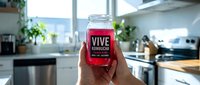 Hand holding red smoothie jar with label in modern kitchen interior with natural lighting and contemporary appliances for healthy lifestyle concept.