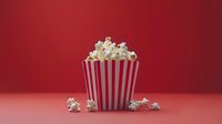 Fresh popcorn in classic red and white striped container on coral background with scattered kernels, styled for cinema and entertainment marketing.