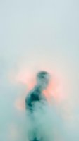 Blurred silhouette of a person emerging from soft pastel mist with teal and pink tones, conveying mystery and ethereal atmosphere for conceptual and artistic projects.