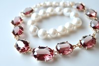 Elegant pearl bracelet and pink crystal necklace set on white background, featuring oval-cut stones in rose gold settings and lustrous white pearls. Luxury jewelry.