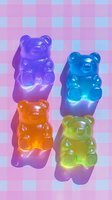 Colorful gummy bear candies arranged on pink checkered background with dramatic lighting creating glowing effect and strong shadows. Sweet treat composition.