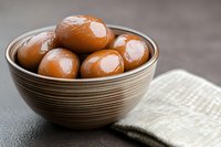 Fresh brown eggs in ceramic bowl with natural linen napkin on dark background, selective focus. Food photography for cooking blogs and recipe websites.