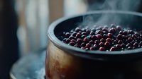Fresh ripe blueberries steaming in rustic metal pot with rising vapor, moody dark food photography with natural window lighting and shallow depth of field.