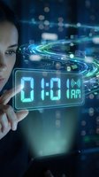 Young woman interacting with futuristic digital clock display showing 01:01 AM in glowing blue interface with holographic technology elements.