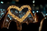 Young couple holding glowing heart-shaped sparkler at night creating romantic atmosphere with bokeh lights background for Valentine's Day celebration.
