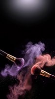 Professional makeup brushes with colorful powder explosion on black background for beauty and cosmetics advertising campaigns.