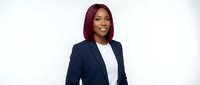 Professional African American businesswoman with burgundy hair in navy blazer and white top smiling confidently on white background for corporate use.