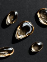 Golden liquid drops with glitter particles on dark background casting dramatic shadows, luxury cosmetic concept for skincare and beauty products.