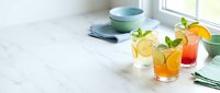 Fresh summer cocktails with mint garnish on marble counter near window, colorful refreshing drinks for entertaining and hospitality industry use.
