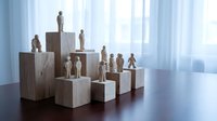 Wooden figurines arranged on geometric blocks creating hierarchy display on polished table near bright window for business leadership concepts.