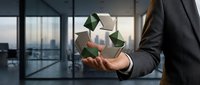 Professional businessman in suit holding floating recycling symbol in modern office environment representing corporate sustainability and environmental responsibility.