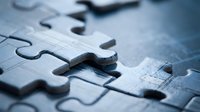 Close-up of jigsaw puzzle pieces connecting on wooden surface. Business teamwork, problem solving and strategic planning concept for presentations.