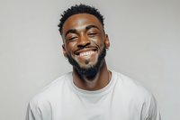 Happy young African American man with beard smiling broadly in white t-shirt against neutral background for lifestyle and portrait photography.