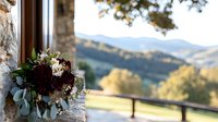 Romantic wedding bouquet with burgundy dahlias and eucalyptus leaves on rustic stone windowsill overlooking mountain landscape in golden autumn light.