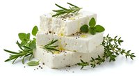 Fresh white goat cheese rounds stacked with aromatic herbs rosemary thyme oregano and black pepper seasoning for gourmet cooking and culinary presentations.