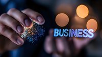 Hand holding glowing network structure with blue neon business text and bokeh lights in dark background, representing digital transformation and connectivity.