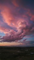 Dramatic pink and purple storm clouds at sunset over vast landscape with winding river creating moody atmospheric sky for weather and nature concepts.