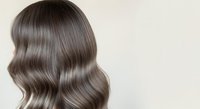 Young woman with long, voluminous wavy hair in ash brown tones, showcasing salon-quality styling and shine. Ideal for hair care, beauty, and wellness marketing materials.