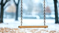 Empty wooden swing in snowy winter park with blurred background, chain suspension and fresh white snow covering ground, nostalgic seasonal scene.