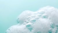 Ocean waves with white foam creating abstract patterns on turquoise water surface. Aerial view of sea foam and bubbles for coastal and marine themes.