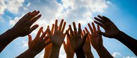 Diverse hands reaching toward bright sunlight against blue sky with clouds, symbolizing unity, teamwork, hope, and community support in uplifting moment.