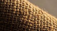 Natural burlap fabric texture with woven jute fibers in warm brown tones, perfect for rustic crafts, packaging design, and eco-friendly branding projects.