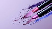 Pink and purple lipsticks with scattered powder makeup pigments on light background creating artistic cosmetic composition for beauty and fashion industry.