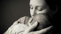 Tender mother holding newborn baby in intimate embrace, peaceful bonding moment between parent and infant in soft monochrome portrait for family concepts.
