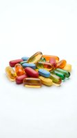 Colorful vitamin supplements and pills scattered on white background for health and wellness concepts.