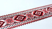 Traditional Ukrainian embroidery pattern with red and black geometric motifs on white fabric. Folk art cross-stitch design for cultural crafts and textile decoration.