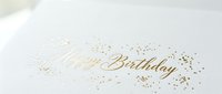 Elegant Happy Birthday greeting card with gold foil calligraphy script and sparkling confetti dots on white textured paper background.