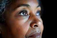 Close up portrait of African American woman's eyes and face in dramatic side lighting, capturing contemplative expression and natural skin texture.