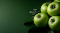 Fresh green apples with water drops on dark background with copy space. Natural organic fruit composition with dramatic lighting and leaves.