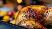 Golden roasted turkey with crispy skin and herbs in kitchen setting. Holiday feast preparation for Thanksgiving or Christmas dinner celebration.