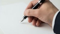 Businessman hand writing with elegant fountain pen on white paper, signing contract or document in office setting.