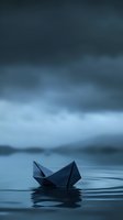 Paper boat floating on dark moody water surface with ripples and stormy clouds above, creating atmospheric minimalist scene in blue tones.