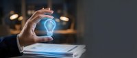 Businessman holding glowing light bulb above tablet, representing innovation, creativity, and digital technology solutions for business growth and development.