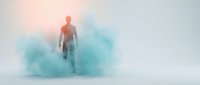 Male figure in orange shirt standing amid turquoise powder explosion on white background, isolated for design use on apparel and marketing materials.