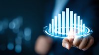 Businessman touching holographic bar chart with glowing blue technology interface against dark background for financial data analysis and business intelligence.