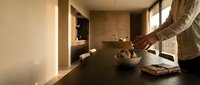 Woman preparing healthy breakfast in modern minimalist kitchen with warm natural lighting and clean contemporary design.