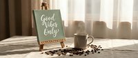 Motivational good vibes only sign on easel with coffee cup and beans in warm sunlight for positive mindset and morning inspiration decor.