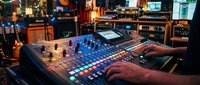 Music producer working on digital audio equipment in professional studio with colorful control panel and mixing console for sound engineering and music production.