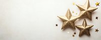 Golden decorative stars and small confetti scattered on white background, creating festive holiday atmosphere for celebration designs and greeting cards.